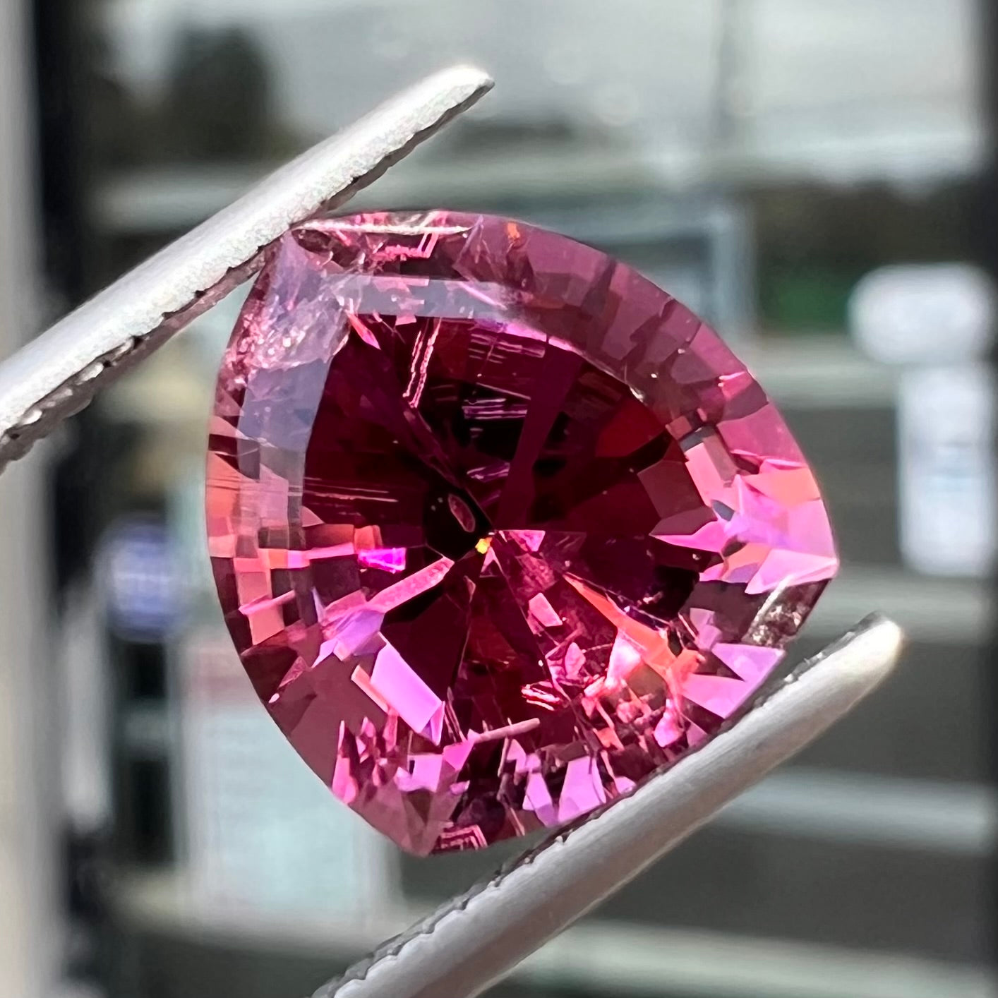 A loose, rounded trillion shield cut pink tourmaline gemstone.