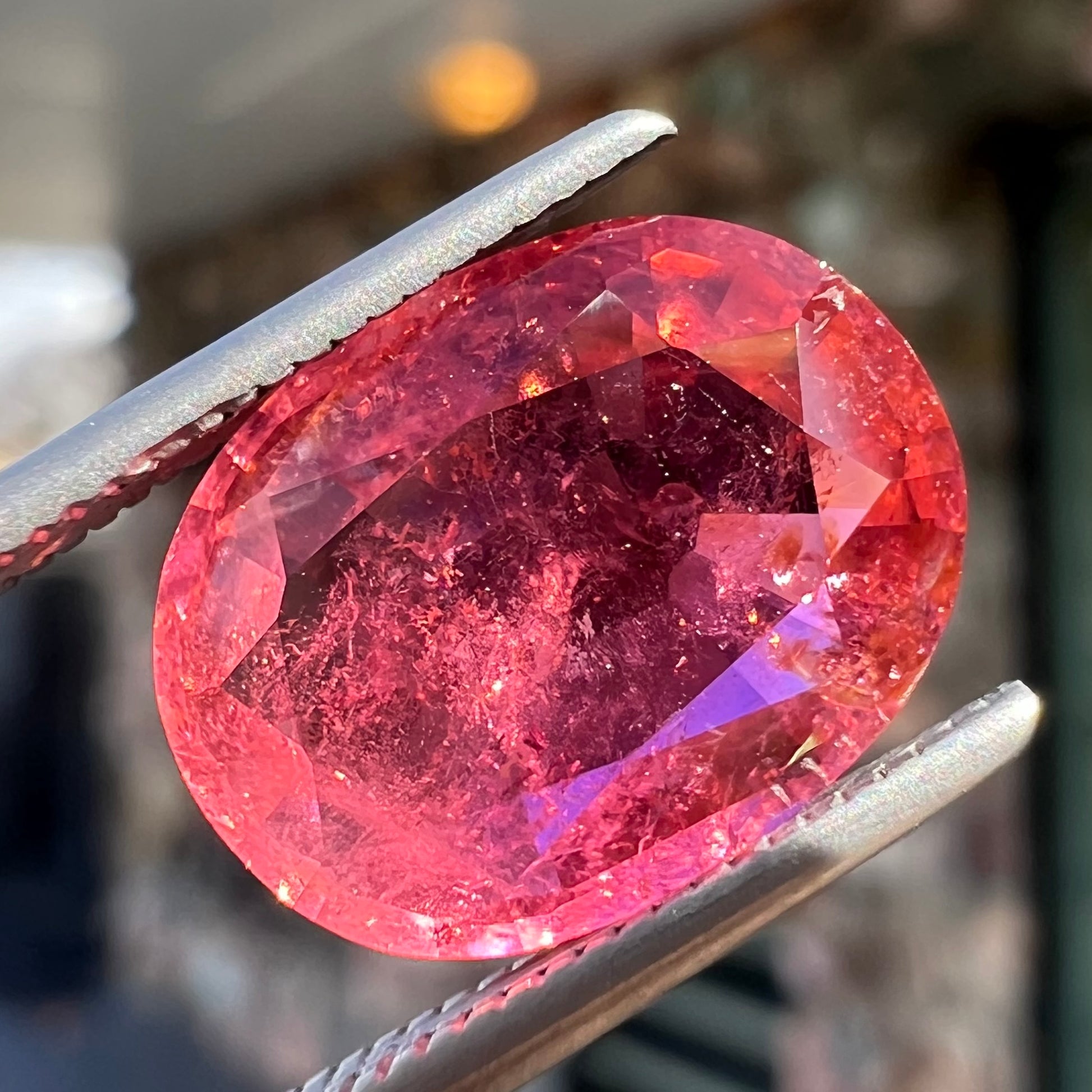 A faceted, oval cut, melon pink tourmaline gemstone.