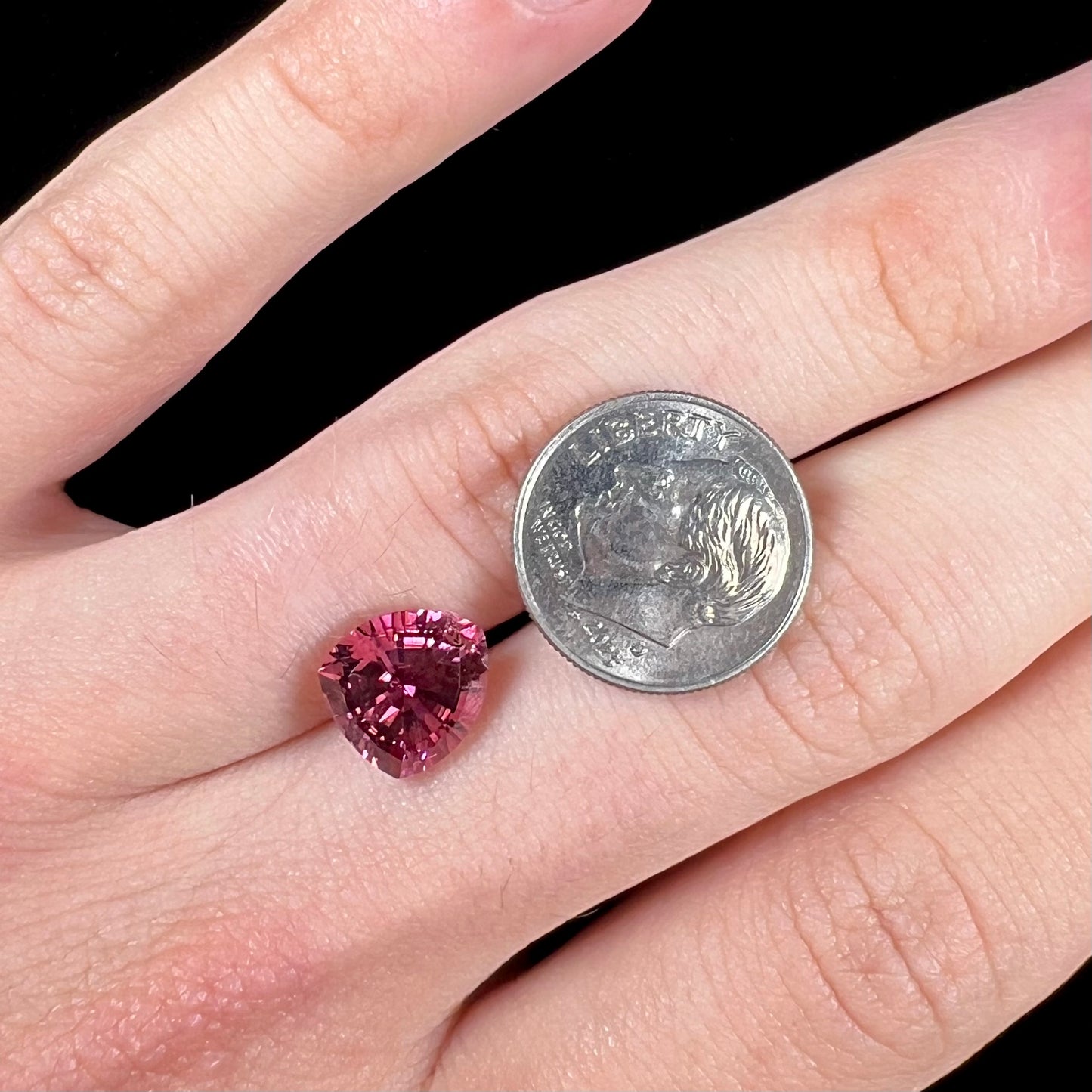 A loose, rounded trillion shield cut pink tourmaline gemstone.