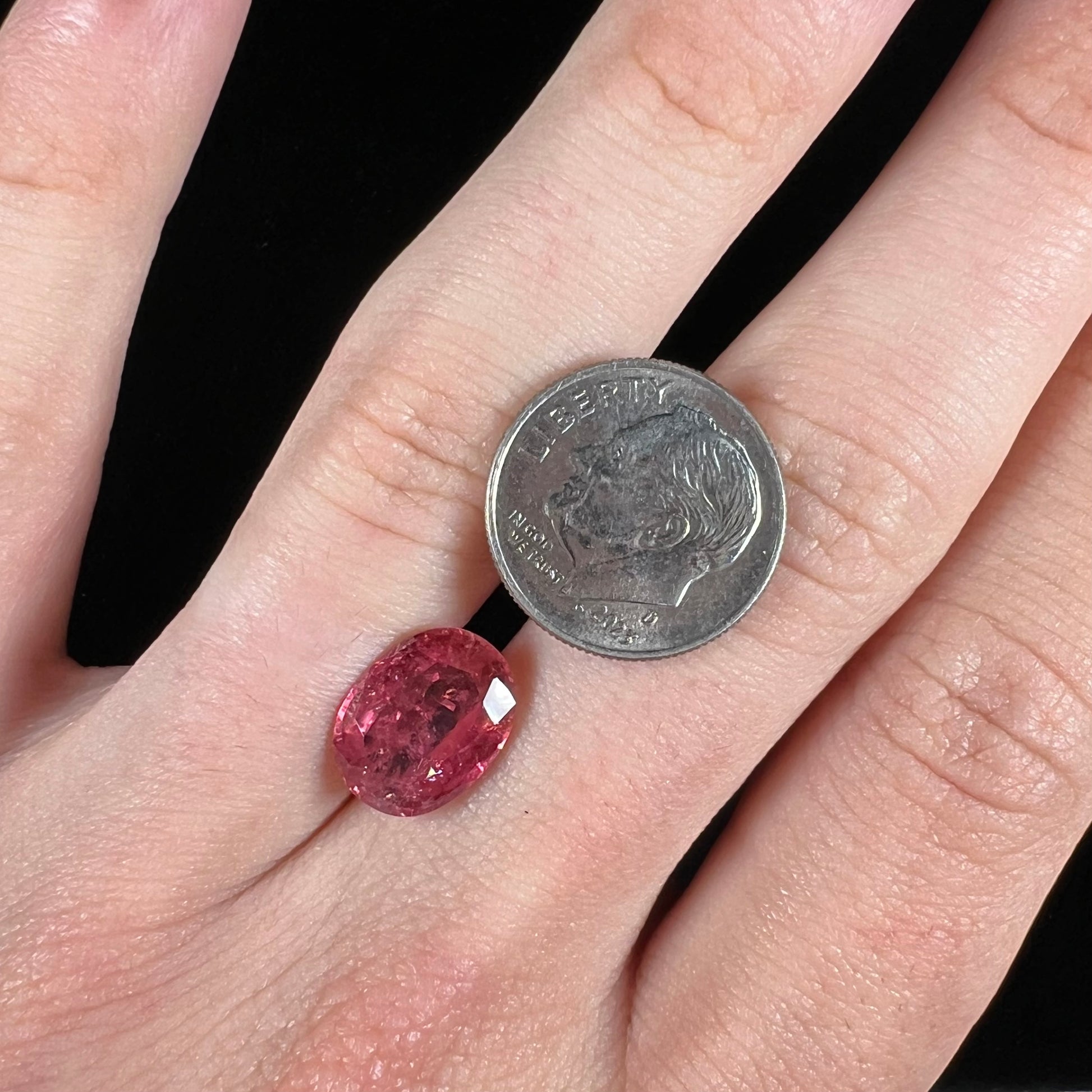 A faceted, oval cut, melon pink tourmaline gemstone.