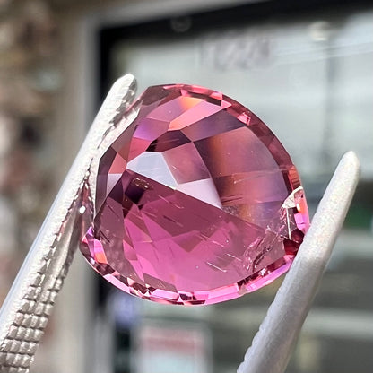 A loose, rounded trillion shield cut pink tourmaline gemstone.