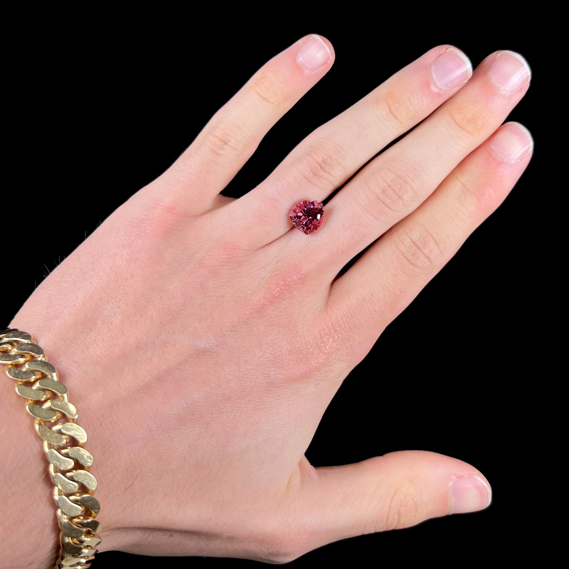 A loose, rounded trillion shield cut pink tourmaline gemstone.