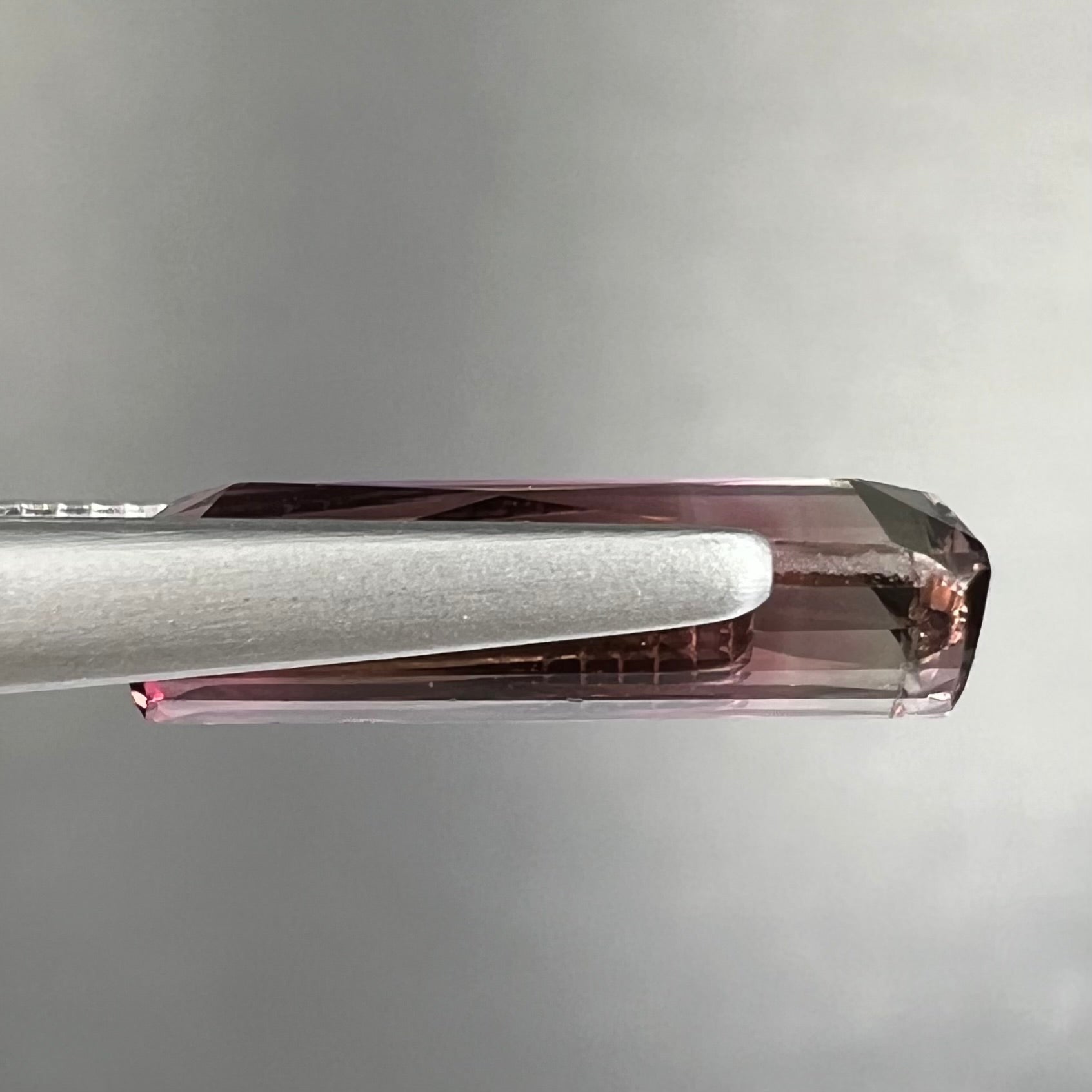 A loose, modified emerald cut tricolor tourmaline.  The stone transitions from pink to light pink to white colors.