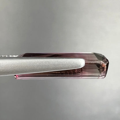 A loose, modified emerald cut tricolor tourmaline.  The stone transitions from pink to light pink to white colors.