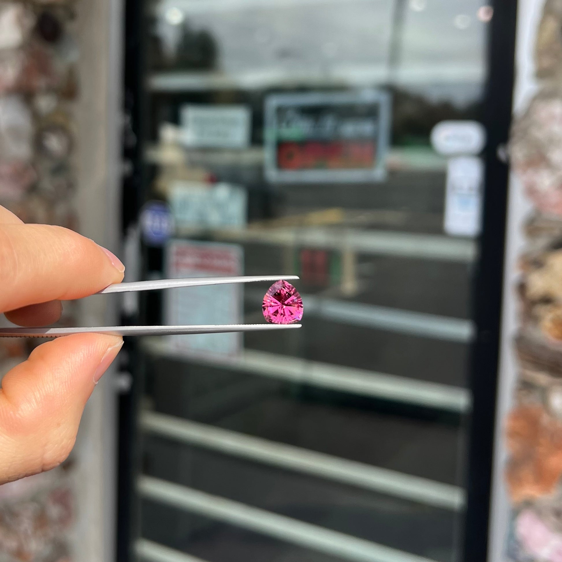 A loose, rounded trillion shield cut pink tourmaline gemstone.