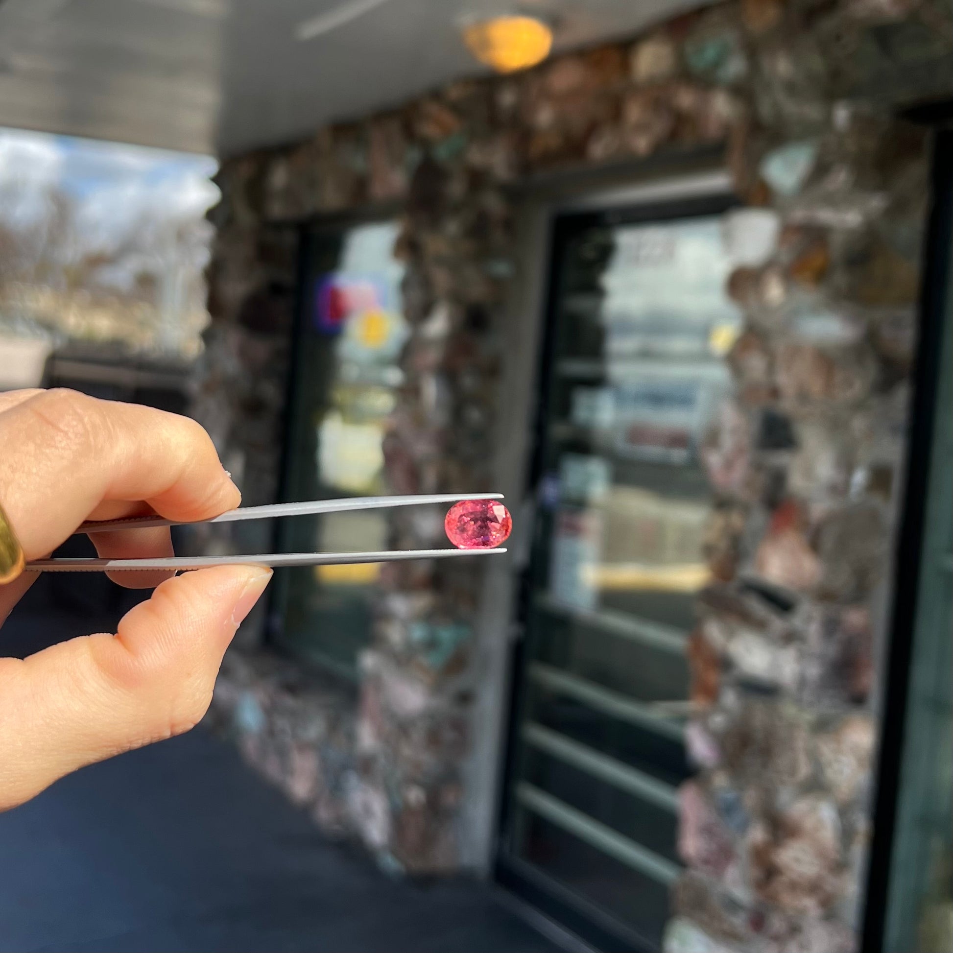 A faceted, oval cut, melon pink tourmaline gemstone.