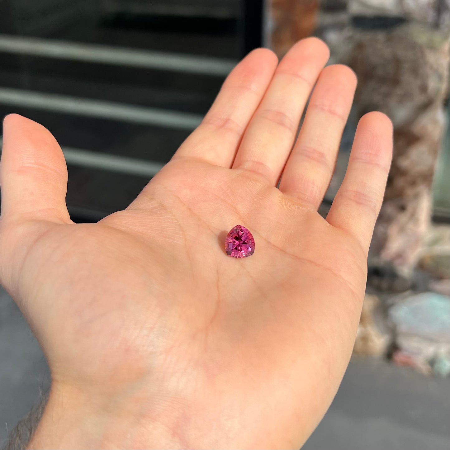 A loose, rounded trillion shield cut pink tourmaline gemstone.