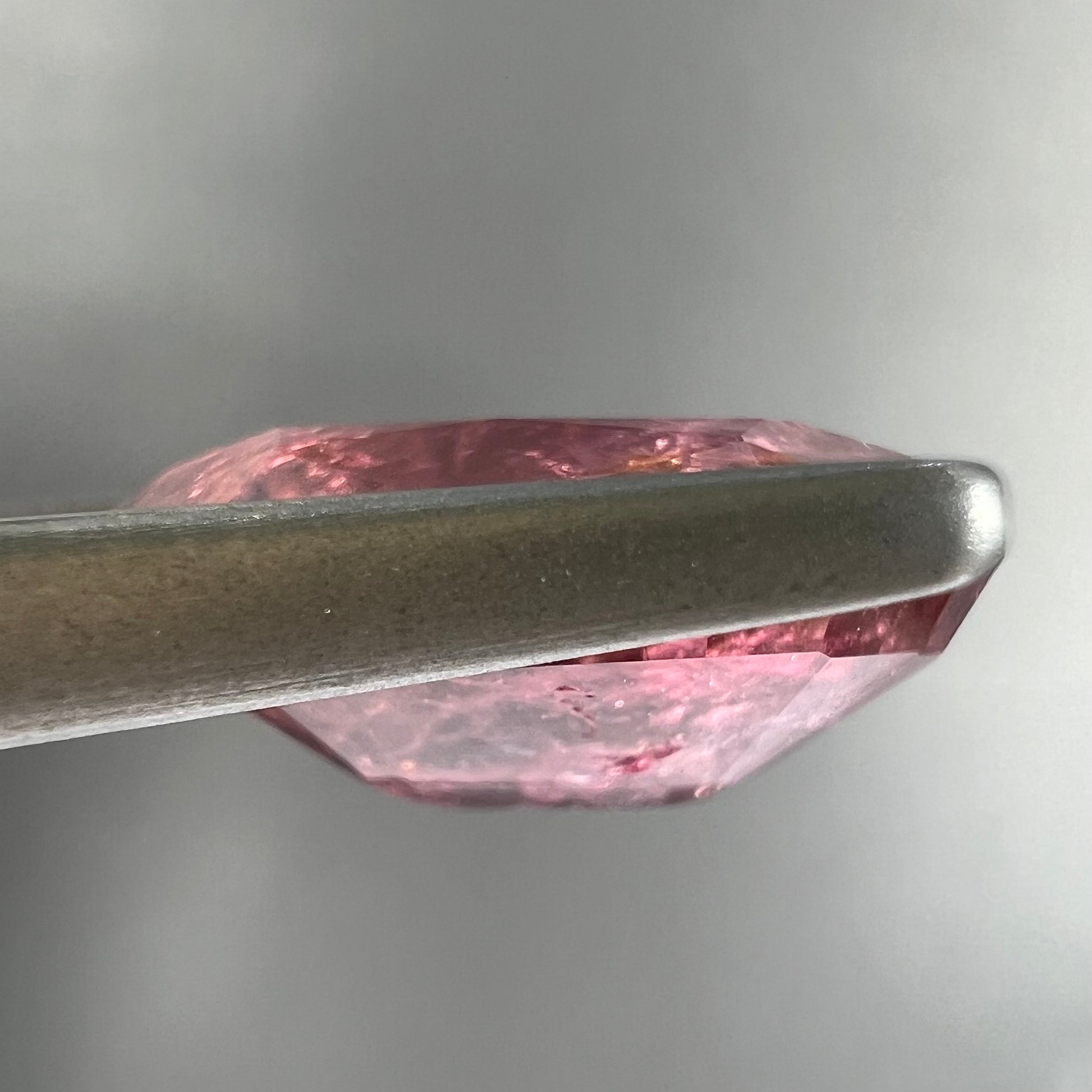 A faceted, oval cut, melon pink tourmaline gemstone.