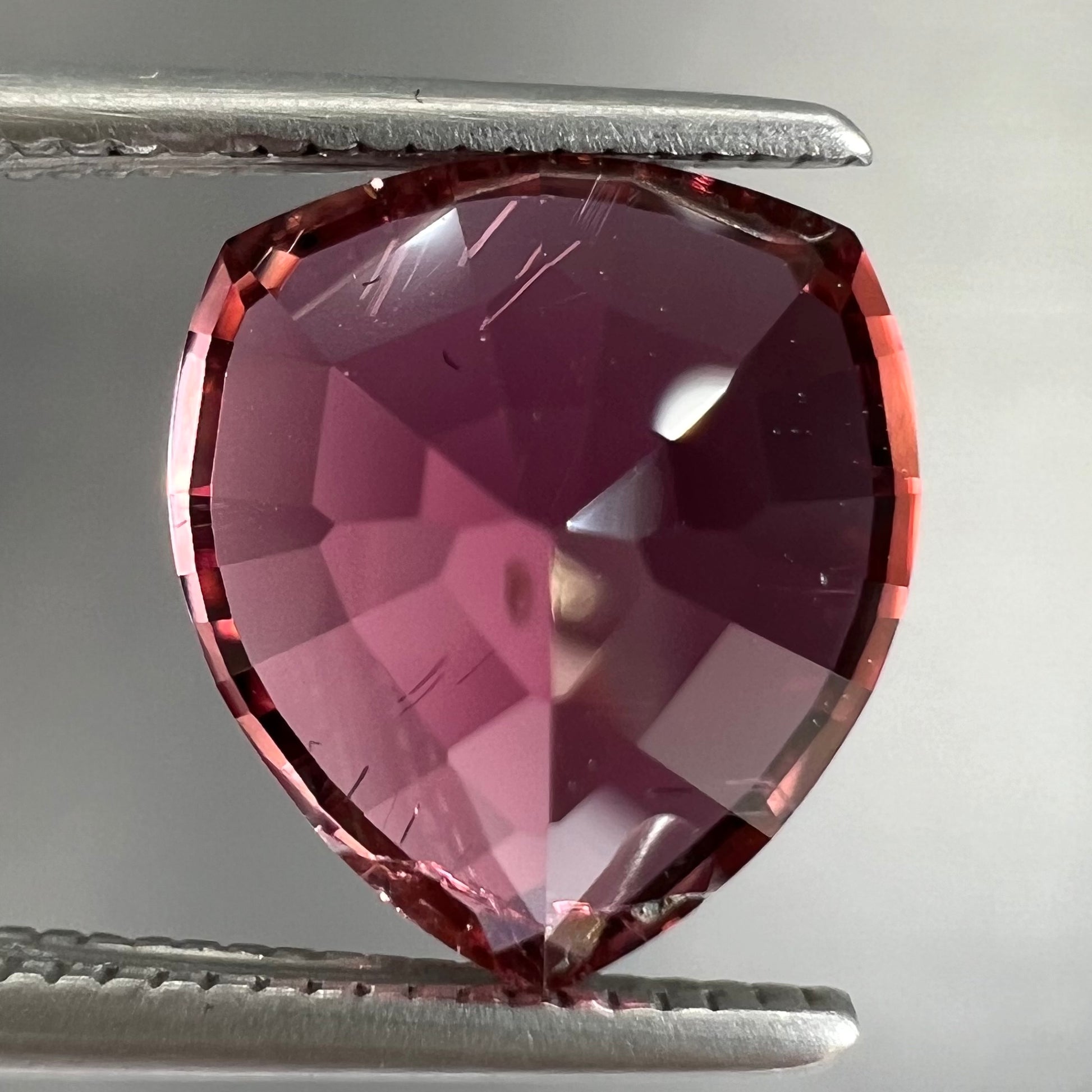 A loose, rounded trillion shield cut pink tourmaline gemstone.