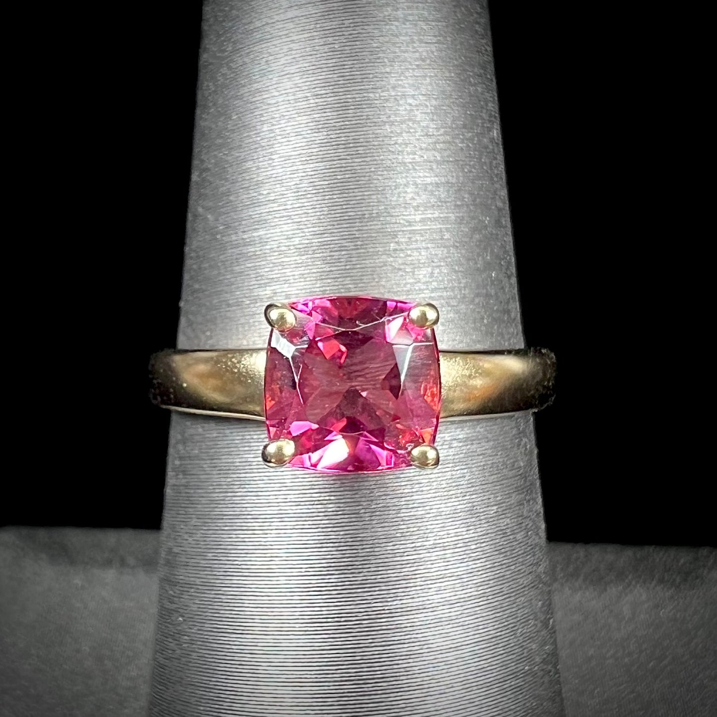 A ladies' cushion cut pink tourmaline solitaire ring in yellow gold.