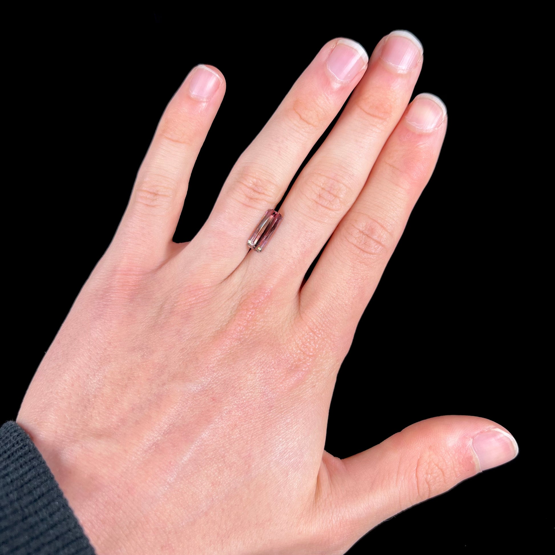 A loose, modified emerald cut tricolor tourmaline.  The stone transitions from pink to light pink to white colors.