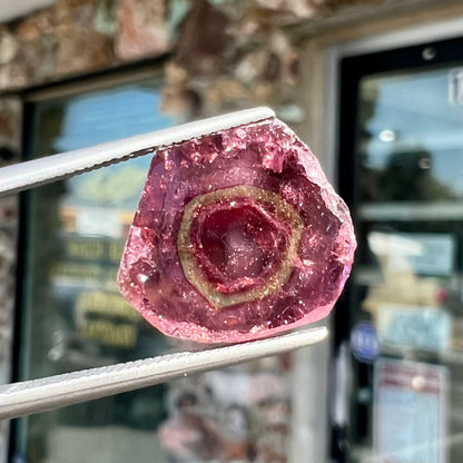 A polished bicolor pink tourmaline crystal slice.