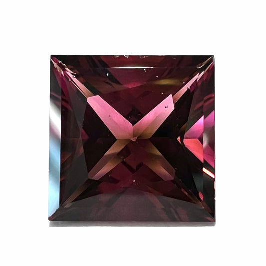 A loose, faceted princess cut tourmaline gemstone.  The stone is a burgundy purple color.