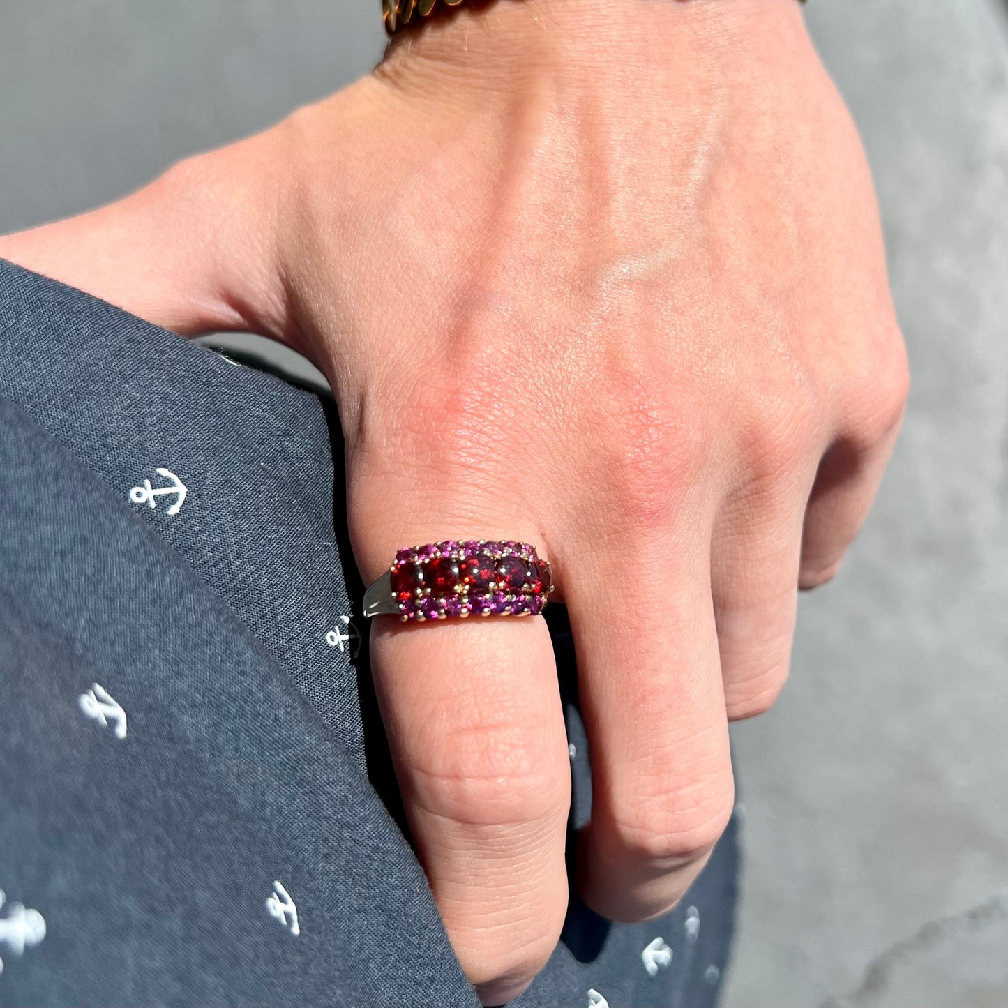 A gold ring set with buff cut cushion shaped almandine garnets with round cut purple rhodolite garnet accents.