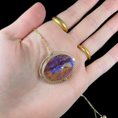 A yellow gold filigree style brooch/pendant combination piece set with a purple opalized wood stone from Duck Creek, Australia.