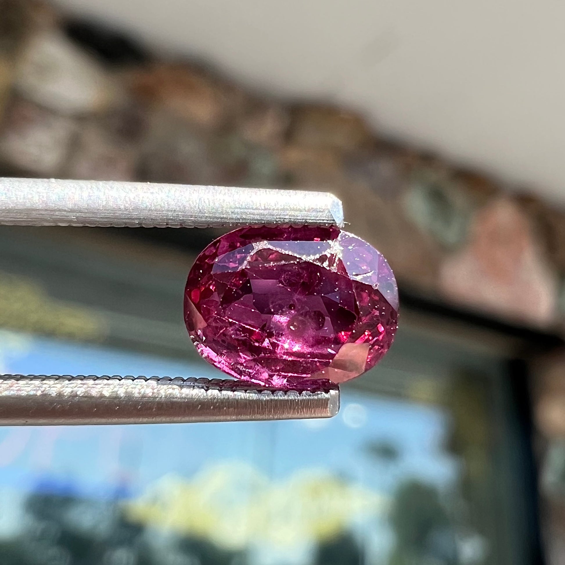 A loose, faceted oval cut natural purple sapphire.  The stone has a burst crystal inclusion.