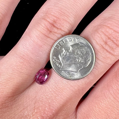 A loose, faceted oval cut natural purple sapphire.  The stone has a burst crystal inclusion.