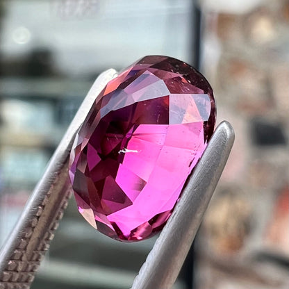A loose, faceted oval cut purple tourmaline gemstone.  The stone weighs 2.08 carats.