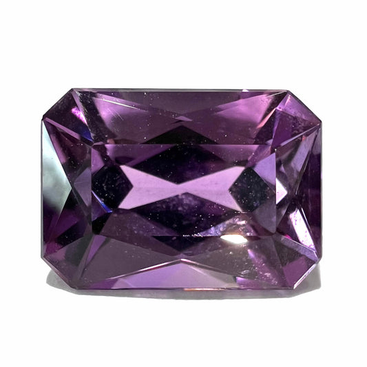 A loose, modified radiant cut amethyst stone.