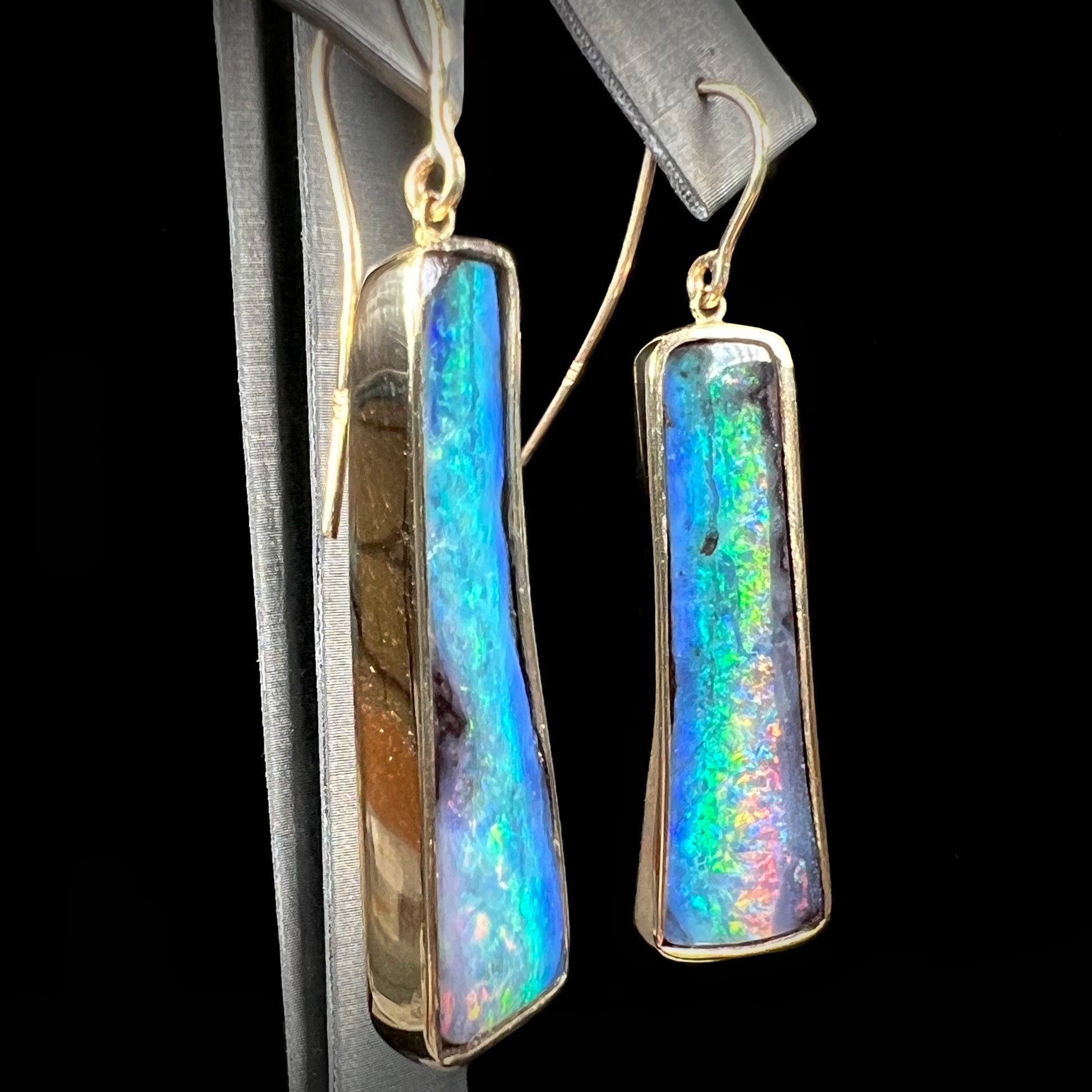 A pair of natural boulder opal dangle earrings set in yellow gold.  The opal displays a rainbow of colors and is from Bull Creek, Australia.