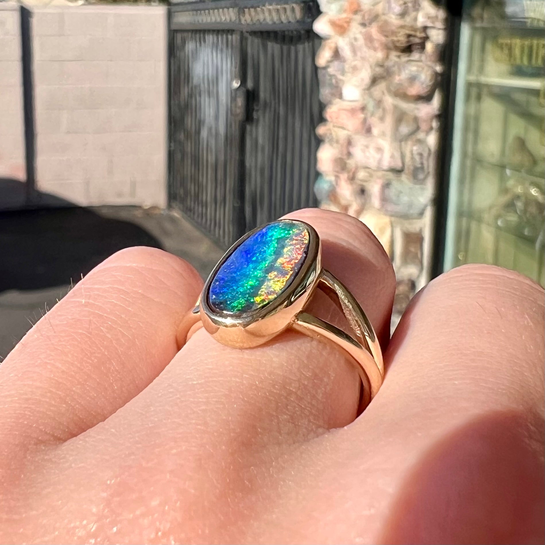 A ladies' yellow gold split shank solitaire ring set with a natural Australian black boulder opal.