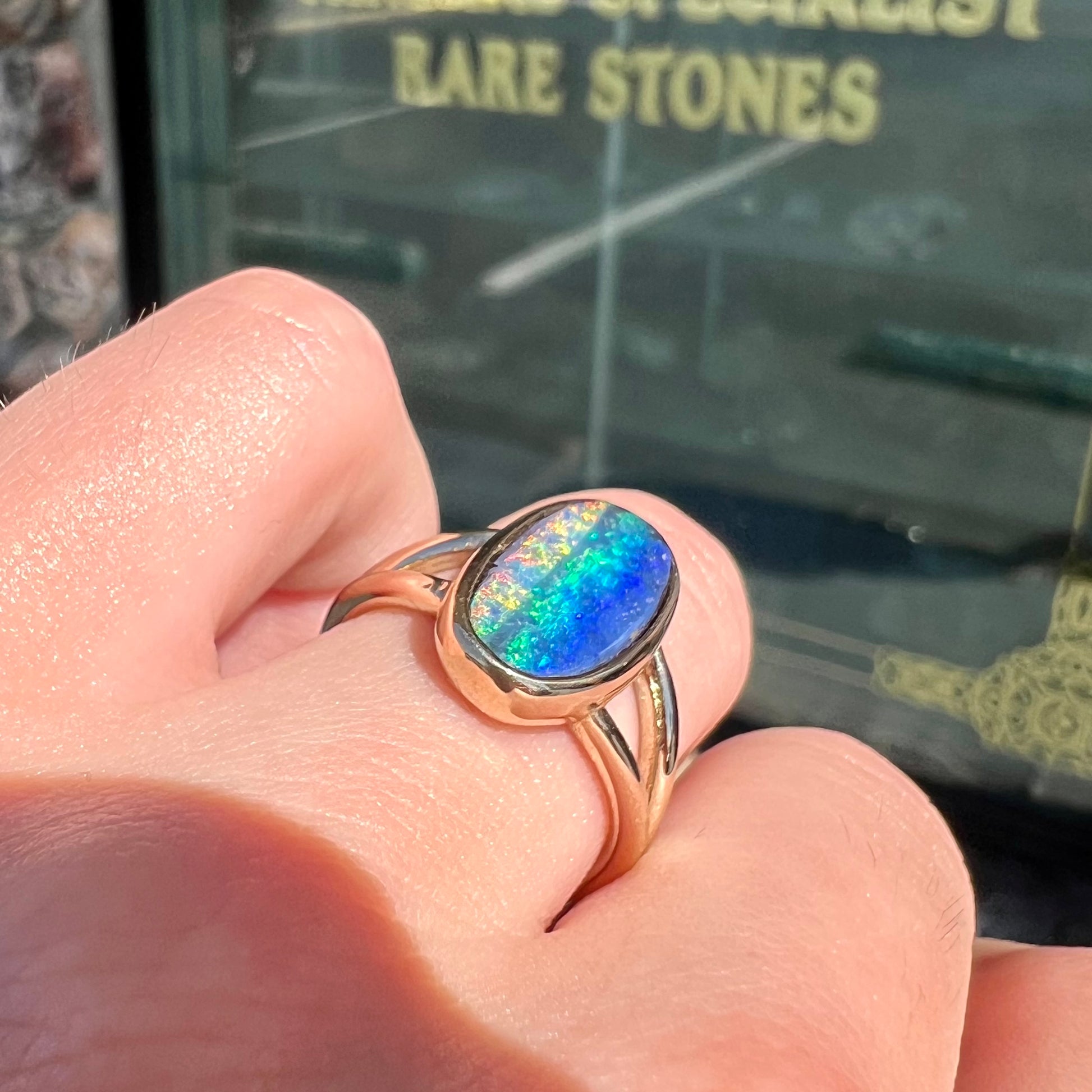 A ladies' yellow gold split shank solitaire ring set with a natural Australian black boulder opal.