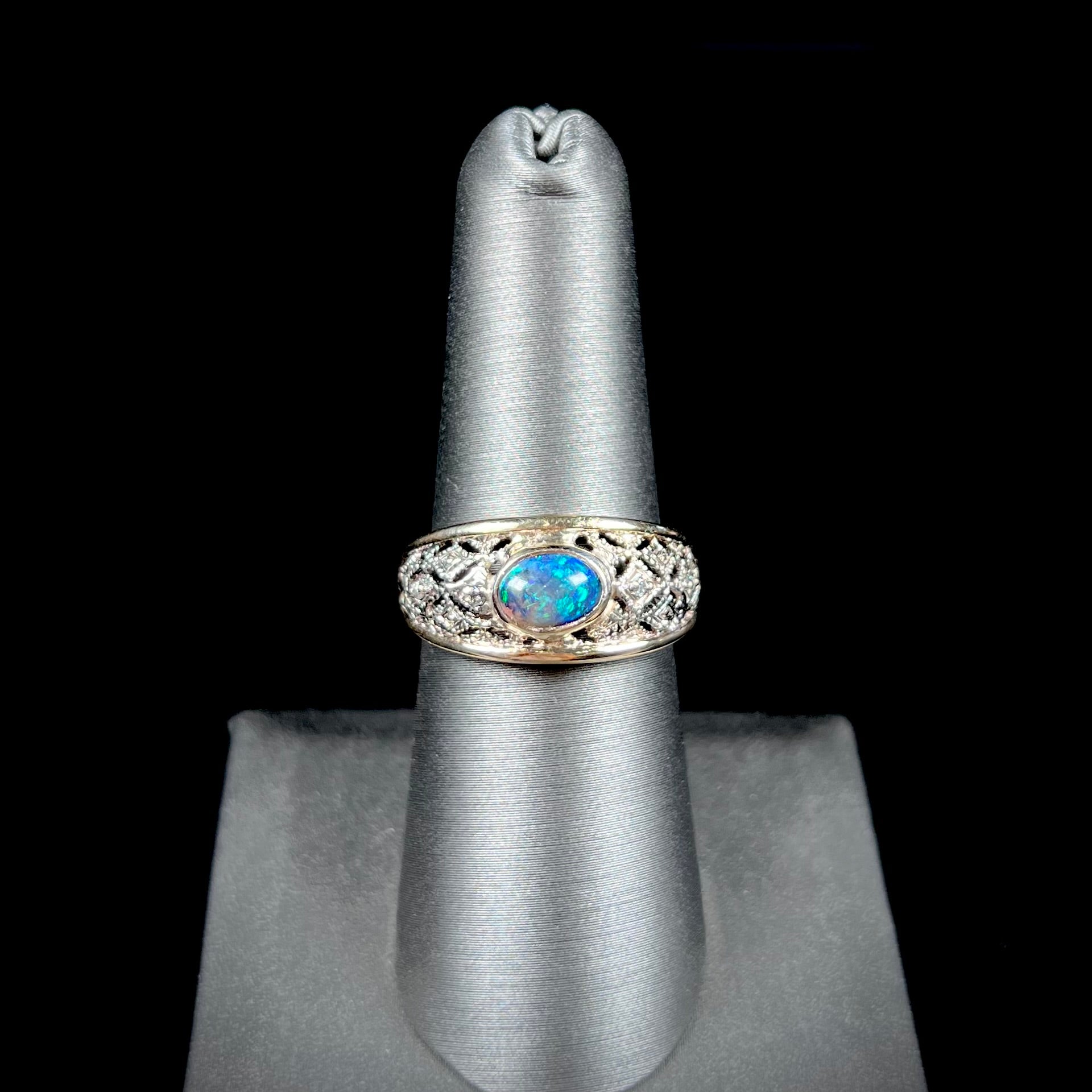 A ladies' yellow gold filigree style ring set with a natural black opal and diamond accents.