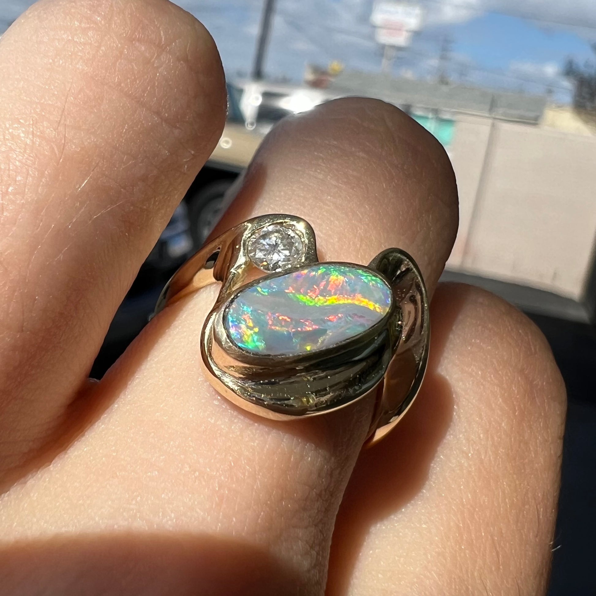 A ladies' yellow gold, bezel set ring mounted with a natural 1.15 carat black opal and round diamond.