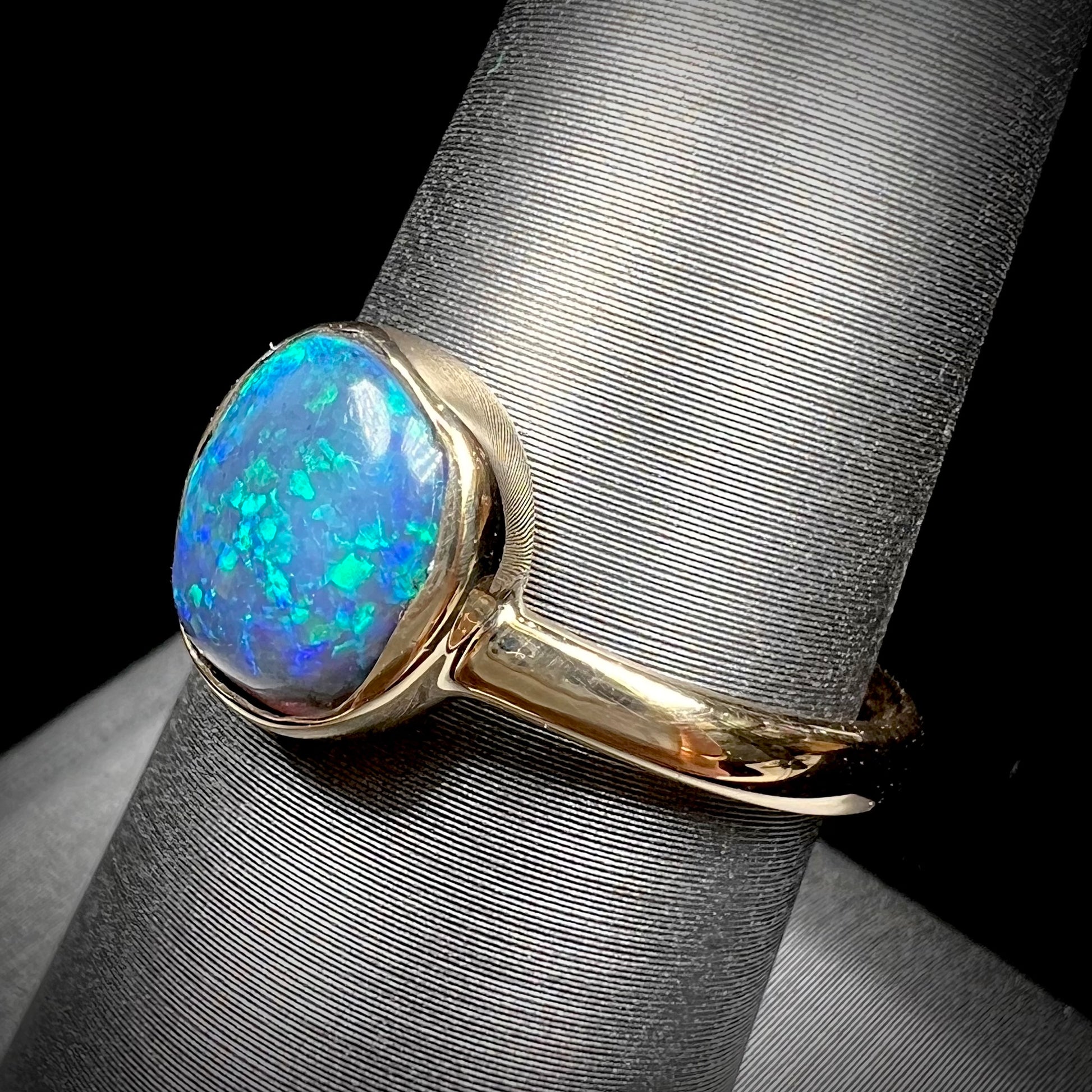 A ladies' natural black crystal opal solitaire ring handmade in 14 karat yellow gold.
