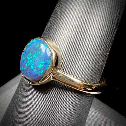 A ladies' natural black crystal opal solitaire ring handmade in 14 karat yellow gold.