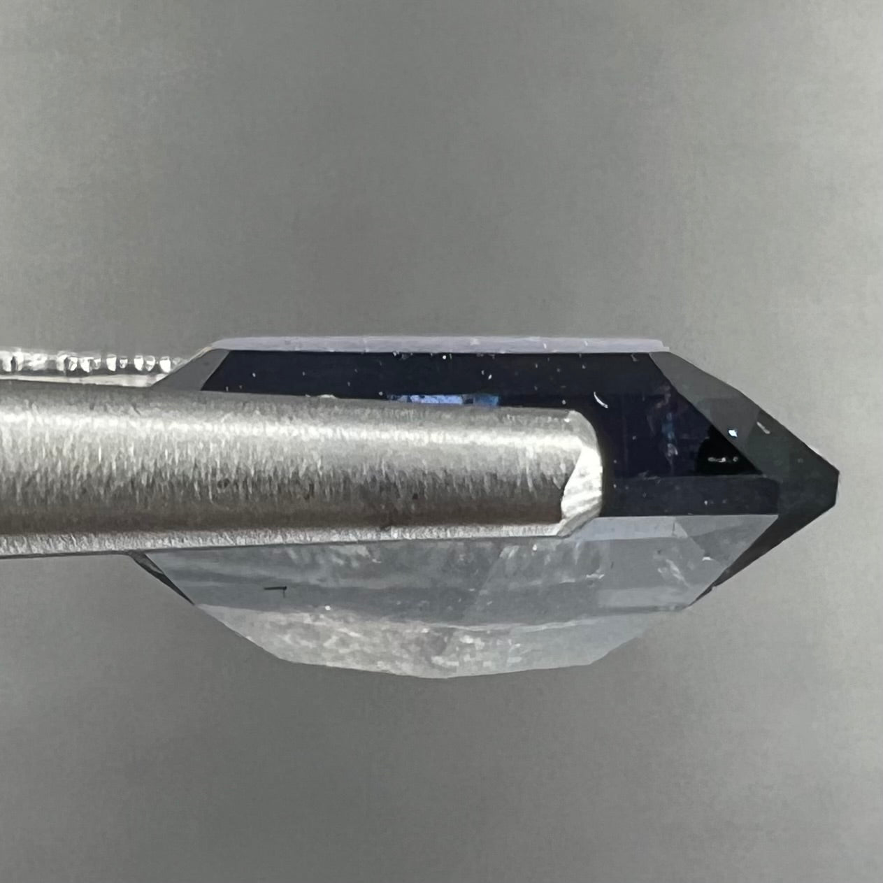 A loose, modified emerald cut, natural color change sapphire stone.  The stone shifts from black to blue to purple to green.