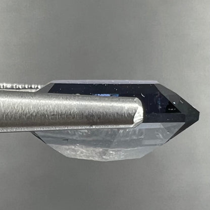 A loose, modified emerald cut, natural color change sapphire stone.  The stone shifts from black to blue to purple to green.