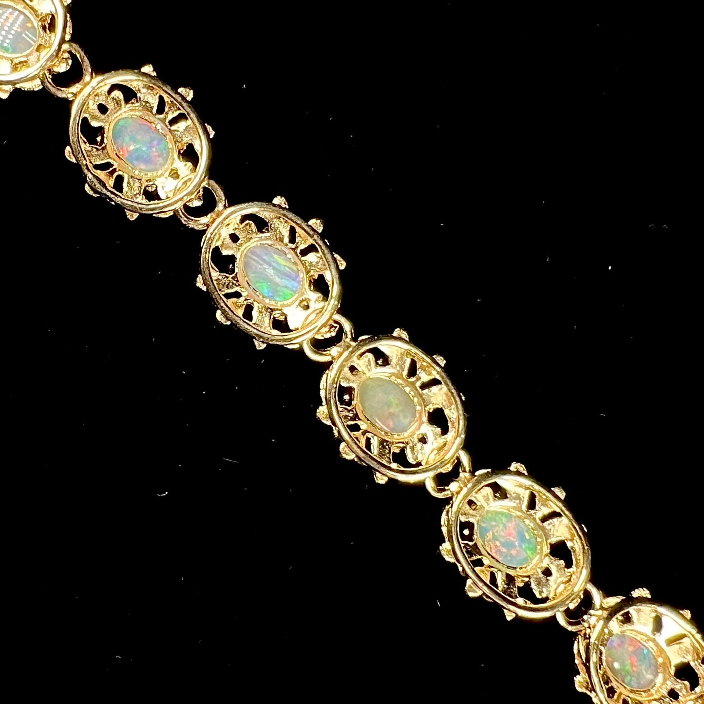 A ladies' yellow gold bracelet set with natural, oval cabochon cut white crystal opals.
