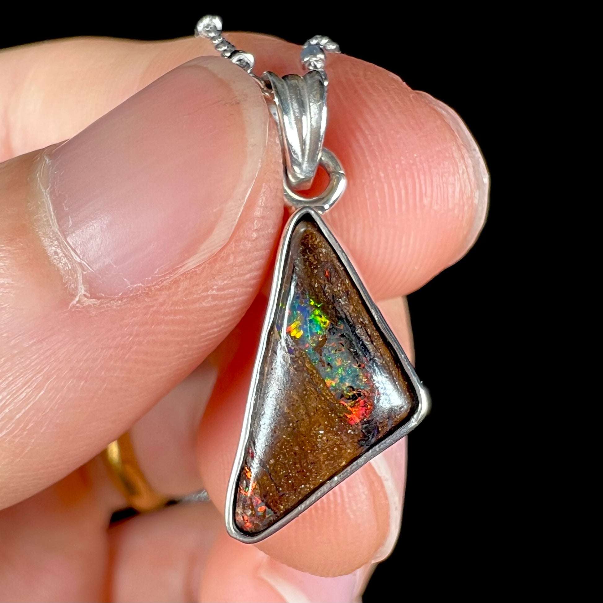 A triangle shaped opal necklace in sterling silver.  The opal shines with every color of the rainbow.
