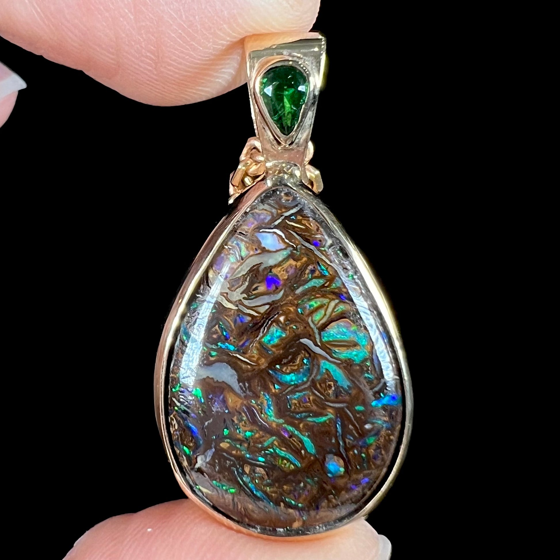 A ladies' yellow gold pendant set with a natural Koroit, Australian boulder opal and a tsavorite garnet accent stone.