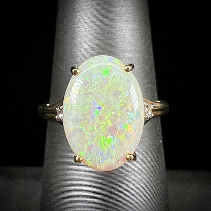 A ladies' yellow gold ring set with two diamonds and an oval cut natural opal stone.