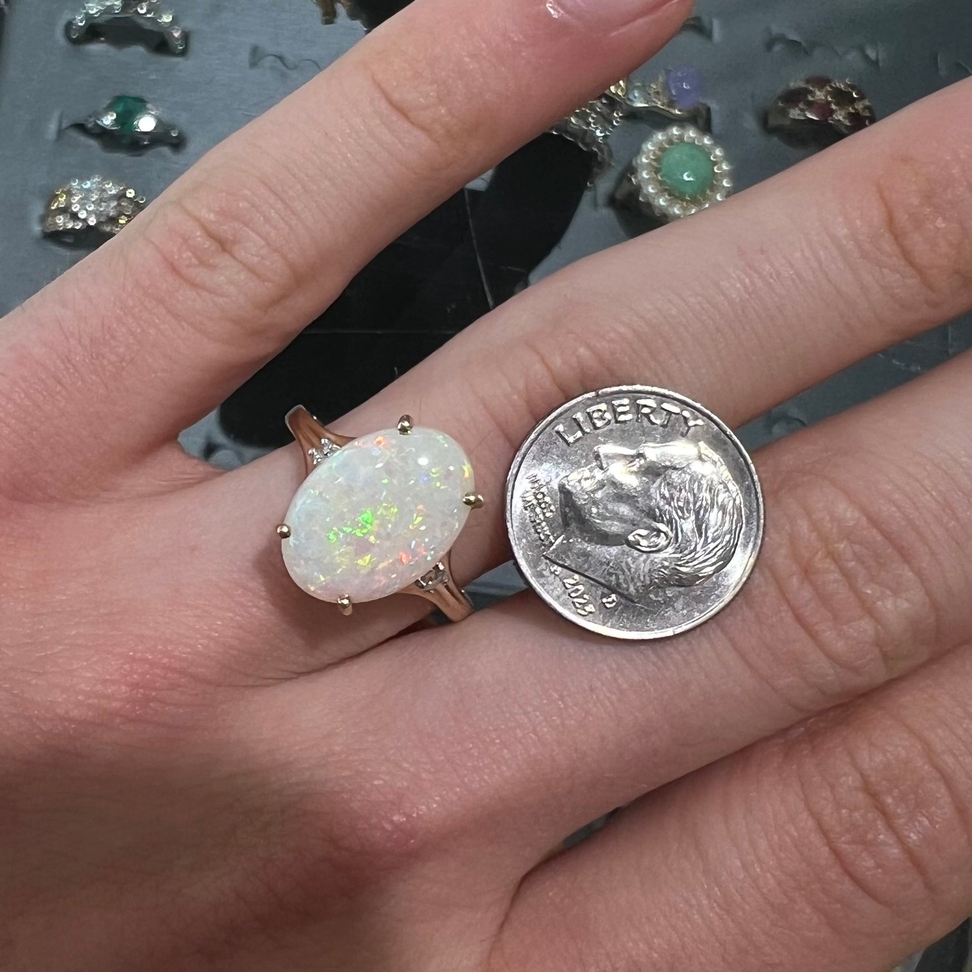 A ladies' yellow gold ring set with two diamonds and an oval cut natural opal stone.