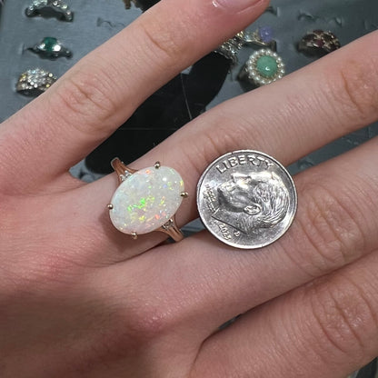 A ladies' yellow gold ring set with two diamonds and an oval cut natural opal stone.