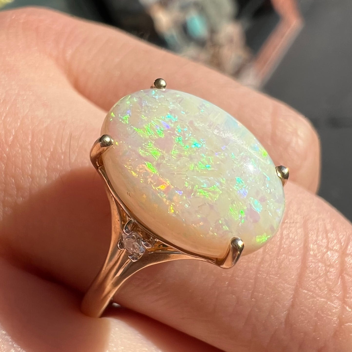 A ladies' yellow gold ring set with two diamonds and an oval cut natural opal stone.