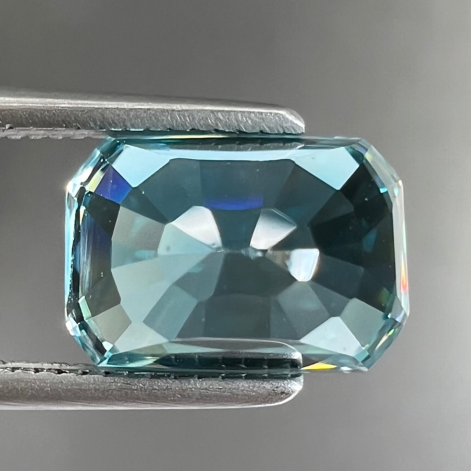 A loose, modified emerald cut blue zircon gemstone.  The stone has a large belly.