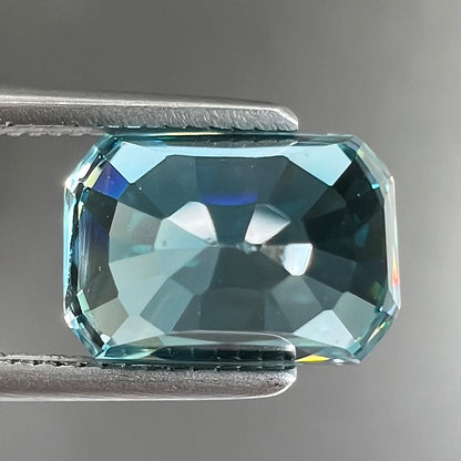 A loose, modified emerald cut blue zircon gemstone.  The stone has a large belly.