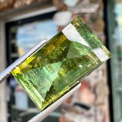 A rectangular step-cut yellowish green tourmaline gemstone.
