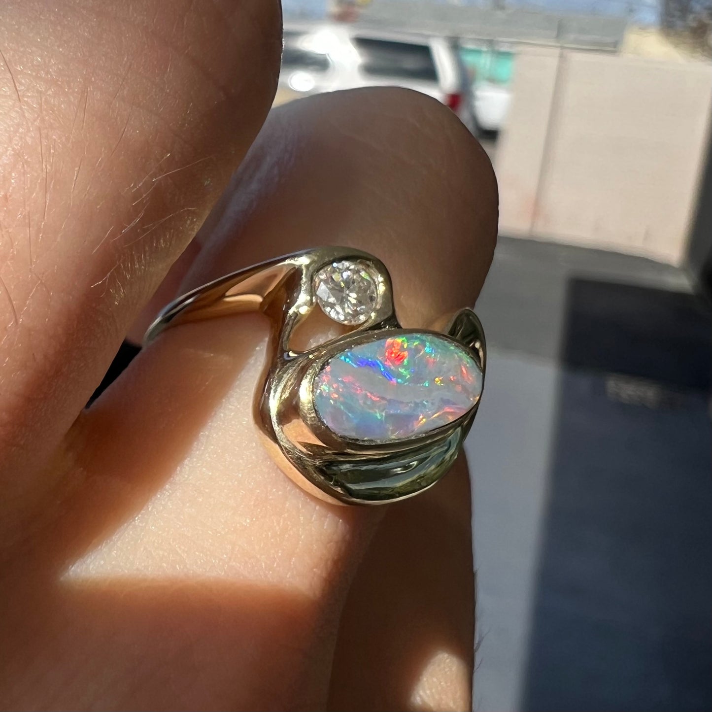 A ladies' yellow gold, bezel set ring mounted with a natural 1.15 carat black opal and round diamond.