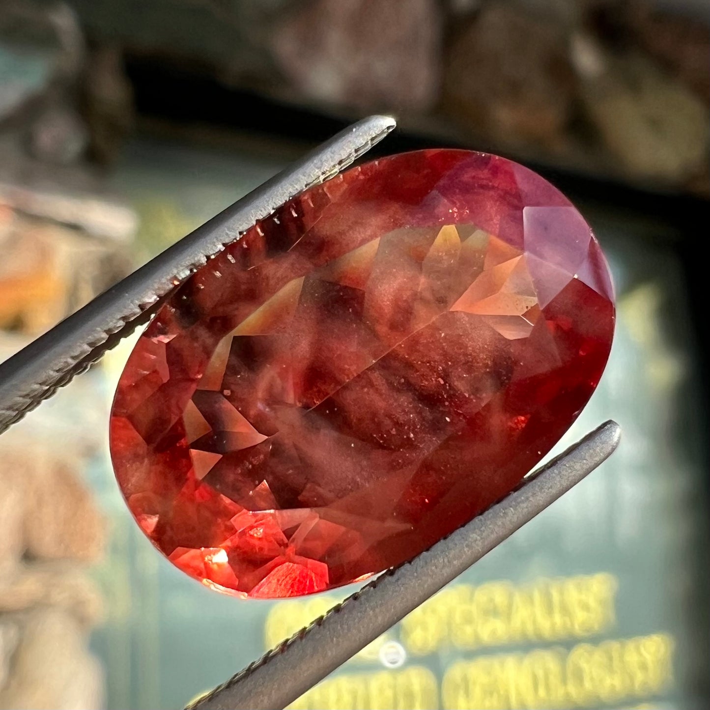 A faceted, oval cut sunstone.  The stone is red-orange color with a bright schiller flash.