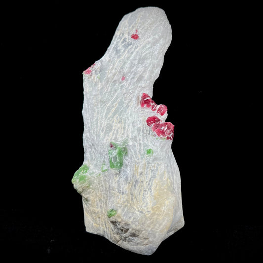 A white calcite specimen embedded with red spinel and green pargasite crystals from Luc Yen District, Vietnam.