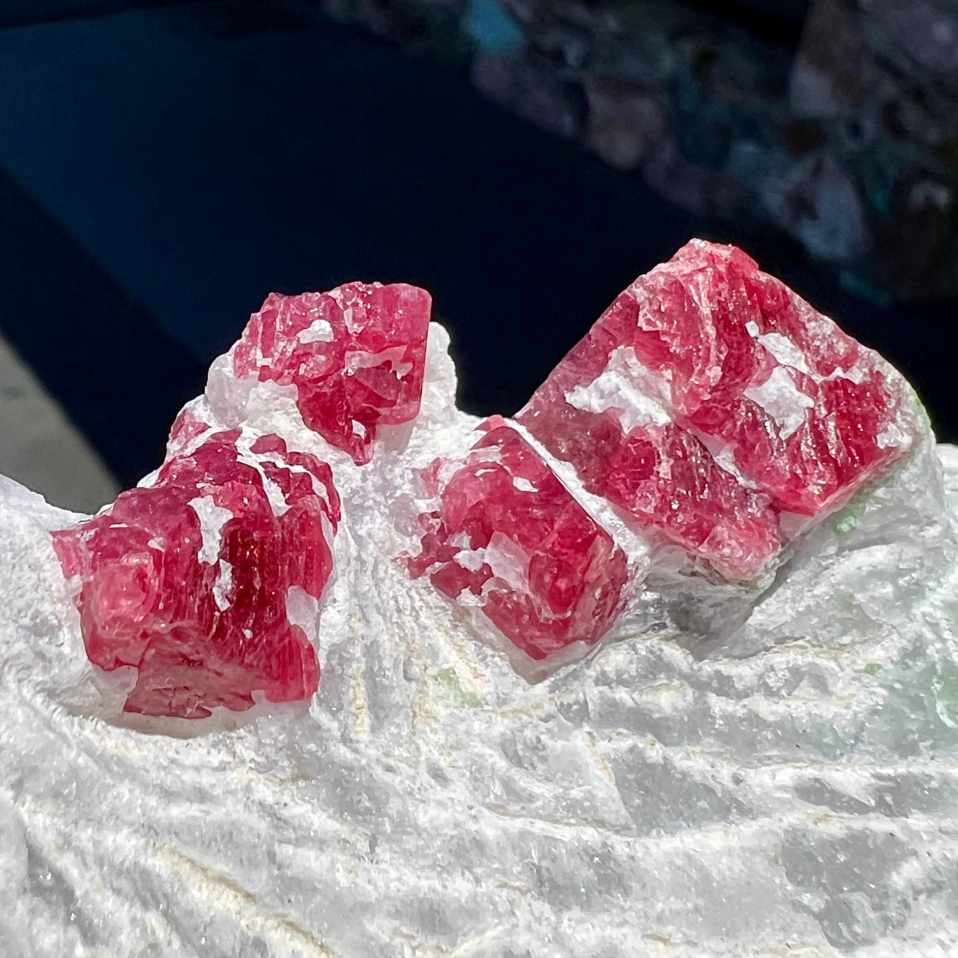 Natural red spinel crystals exhibiting their cubic crystal structure embedded in white calcite matrix.