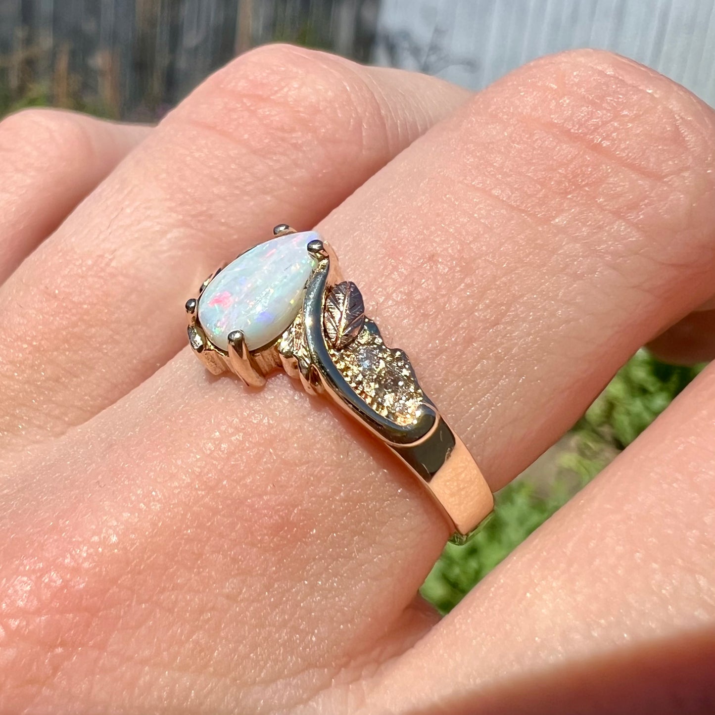 A ladies' two-tone yellow and rose Black Hills gold opal and diamond ring.  The opal is a pear shaped cabochon.