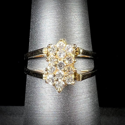 A yellow gold reversible gemstone flip ring.  One side of the ring shows a green gemstone, the other shows a cluster of cubic zirconia.