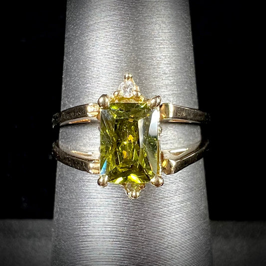 A yellow gold reversible gemstone flip ring.  One side of the ring shows a green gemstone, the other shows a cluster of cubic zirconia.
