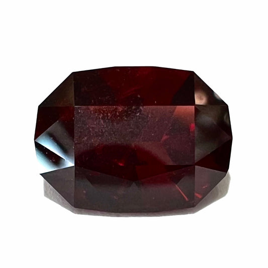 A loose, octagon cut rhodolite garnet gemstone.  The stone is a deep, purplish crimson red color.